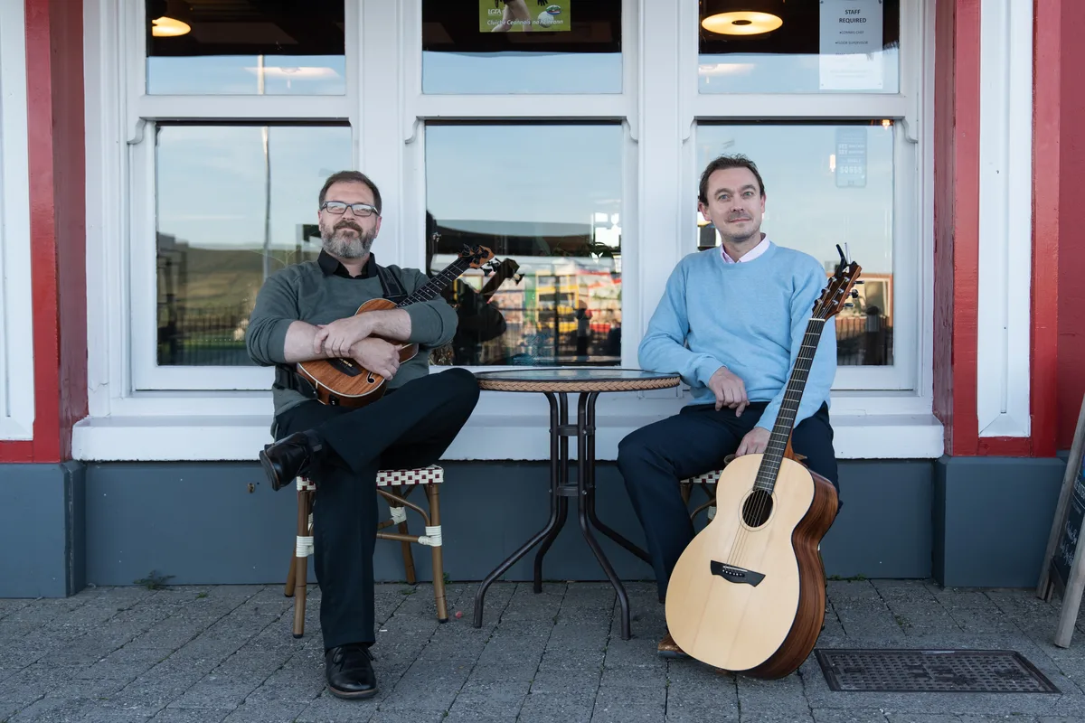 Dave and Tom seated outside a Dingle venue with their instruments